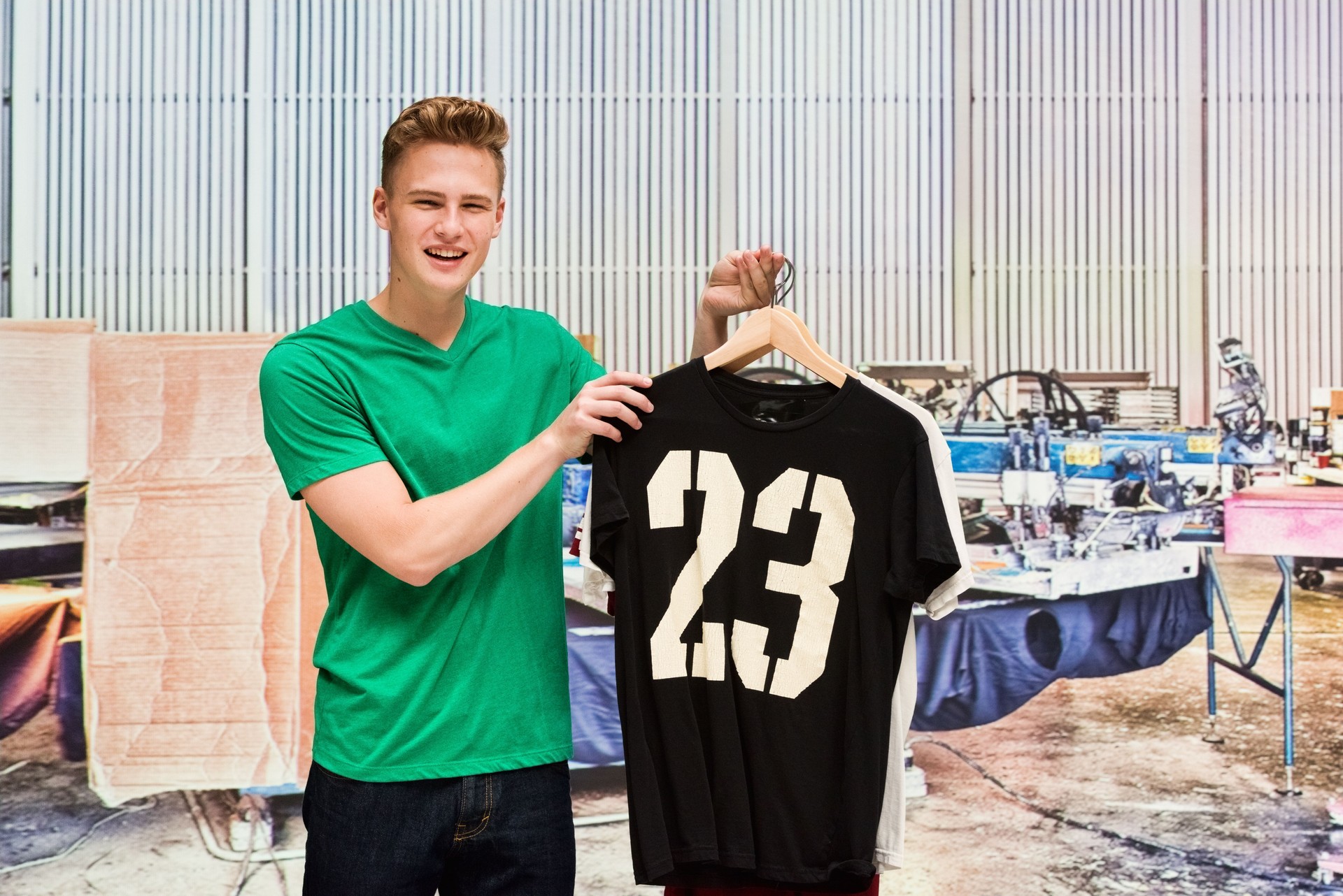Smiling male holding t-shirt in industry